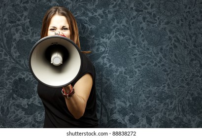 portrait of young woman shouting with megaphone against a vintage wall - Powered by Shutterstock