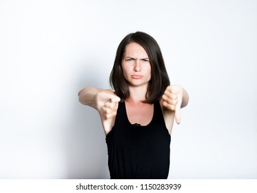 portrait of a young woman showing a thumbs down sign, dislike it, isolated studio photo on a gray background - Shutterstock ID 1150283939