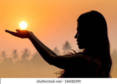 Portrait Of Young Woman As Silhouette And Hand Holding The Sun