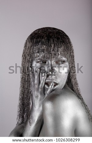 Portrait of young woman with silver beauty body art on gray background