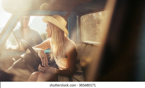 Portrait of young woman sitting in a car talking with friends standing by the car. - Powered by Shutterstock