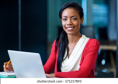 Portrait of young woman sitting at her desk in the office - Shutterstock ID 571217893