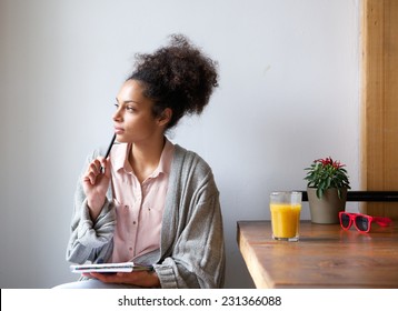 Portrait of a young woman sitting at home with pen and paper