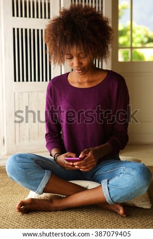 Portrait of a young woman sitting on floor with mobile phone