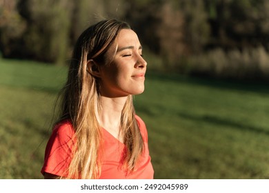 Portrait of a young woman smiling in nature breathing air with her eyes closed. Concept of inner peace and serenity - Powered by Shutterstock