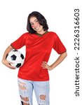 Portrait of young woman smiling with red jersey of her team from her favorite country Morocco holding a soccer ball on white background.