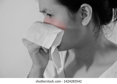 Portrait Of A Young Woman Sneezing In To Tissue. Asian Woman Has Runny And Common Cold. Black And White Photo With Red Dot. People Body Problem Concept