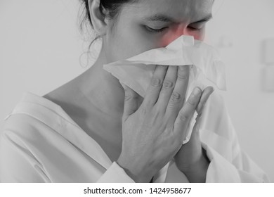 Portrait Of A Young Woman Sneezing In To Tissue. Asian Woman Has Runny And Common Cold. Black And White Photo With Red Dot. People Body Problem Concept