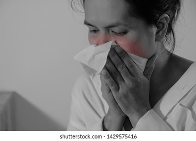 Portrait Of A Young Woman Sneezing In To Tissue. Asian Woman Has Runny And Common Cold. Black And White Photo With Red Dot. People Body Problem Concept