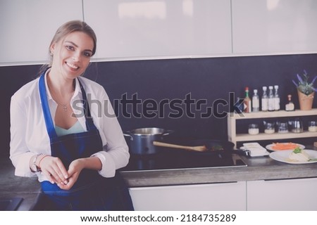 Portrait of young woman standing with arms crossed against kitchen background