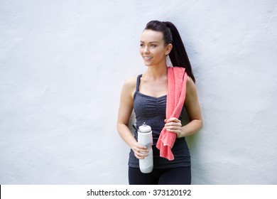 Portrait Of A Young Woman Standing With Towel And Water Bottle After Workout