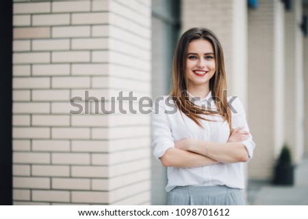 Portrait of young woman in the street with arms crossed