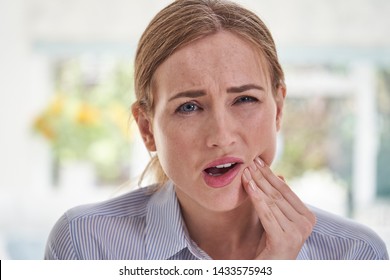 Portrait Of Young Woman Suffering With Toothache Touching Jaw    