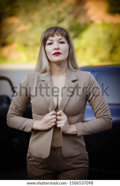 portrait of a\
young woman in a suit next to a\
car