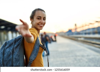 Portrait einer jungen Frau Reisenden mit einem kleinen Rucksack auf der Bahnstation. Frau, die auf den Zug wartet. Folgen Sie mir, aktive und Reise-Lifestyle-Konzept.