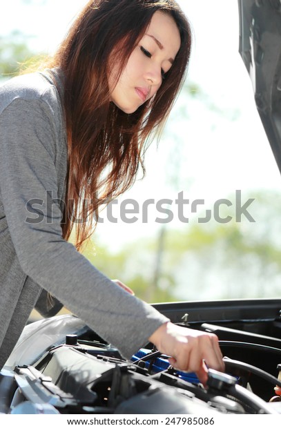 portrait of young woman try to fix engine problem of\
her car