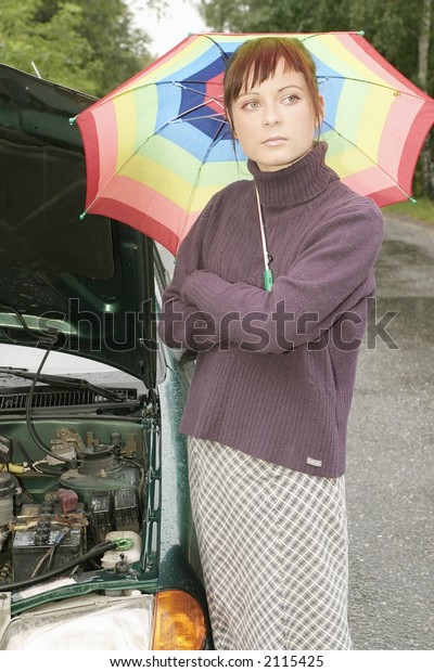 portrait of a young woman with an umbrella, standing\
by a broken car