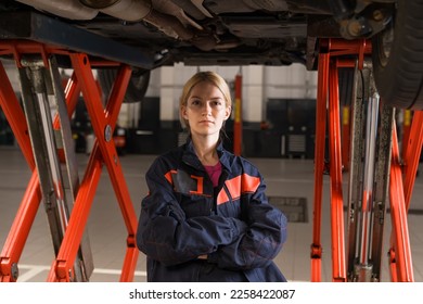 Portrait of a young woman in uniform against the background of a modern car service station. Professional worker, high level of repair - Shutterstock ID 2258422087
