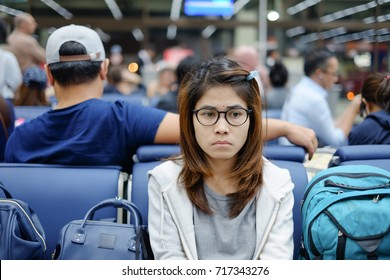 Portrait young woman waiting at gate of airport interior with bored expression on face, Asian Women passenger  is boring after delay and flight cancel or missed