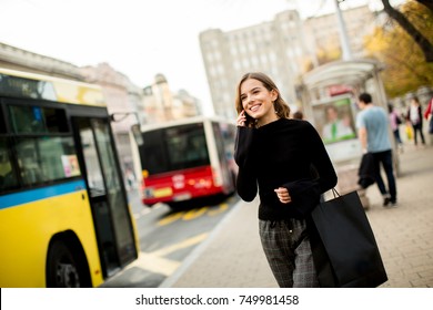 Portrait of young woman waiting for taxi or bus on the street in the city