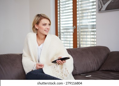 Portrait of young woman watching TV at home sittin on sofa