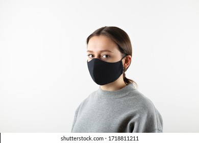 Portrait Of Young Woman Wearing Black Face Mask Isolated On Gray Background. Dust Protection Against Virus. Coronavirus Pandemic Time. Female Looking At Camera