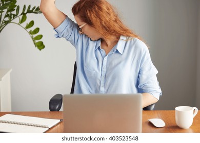 Portrait Of A Young Woman Wearing Blue Shirt Disgusting With Bad Smell Of Her Wet Armpit While Working In The Office. Something Stinks, Negative Human Emotions, Facial Expressions, Feeling Reaction