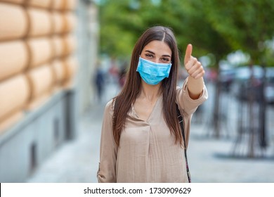 Portrait of young woman wearing face protective mask to prevent Coronavirus and anti-smog. Portrait of young woman wearing face mask. Thumb up. Woman suffer from sick and wearing face mask.