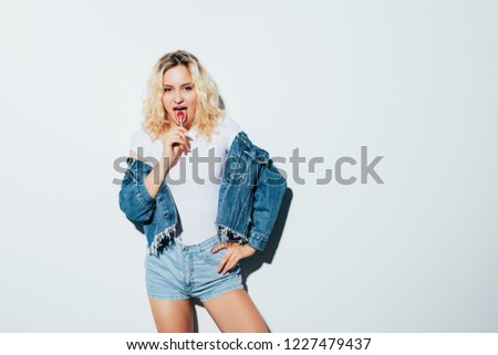 Portrait of a young woman wearing glasses and biting a lollipop isolated on white background