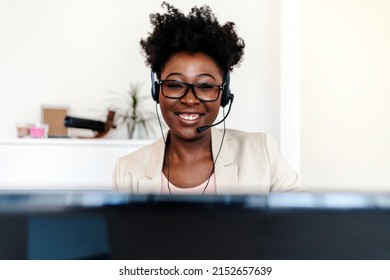 Portrait of a young woman wearing a headset while working on a computer. Woman with a headset, working on a computer at home. Confident young woman using a headset and laptop in a modern office.