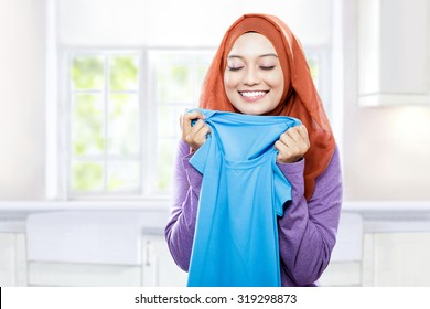 Portrait Of Young Woman Wearing Hijab Holding And Smelling The Fresh Clean Laundry