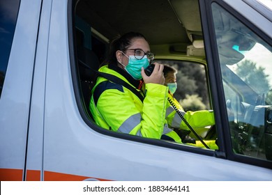 Portrait of a young woman wearing a mask and uniform in an ambulance during a volunteer shift answering an emergency call with her fellow driver - Concept of pandemic from Covid-19, Coronavirus - Powered by Shutterstock