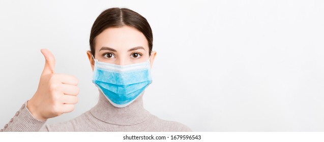 Portrait Of Young Woman Wearing Medical Mask At White Background. Person Is Happy Because She Is Finally Healthy. Protect Your Health. Coronavirus Concept.