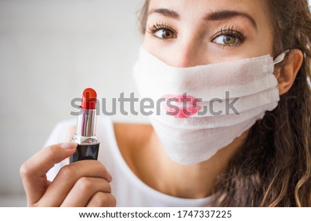 portrait of young woman wearing medical face mask during coronavirus. Make up problem and epidemy. Red lipstick on the protection mask. 
