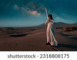 portrait young woman with white dress and lightsaber on a dune in the desert with the milky way in the background