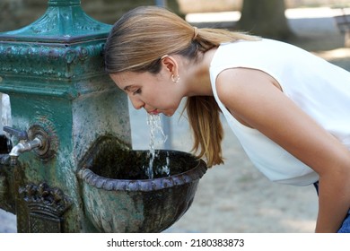 Portrait Of Young Woman Who Hydrates Herself Drinking Water From A Fountain During Heat Wave On Summer