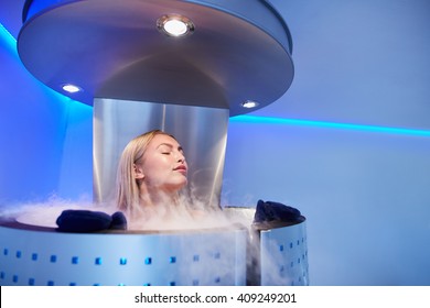 Portrait Of Young Woman In A Whole Body Cryo Sauna. Female Getting Cryo Therapy At The Cosmetology Clinic.