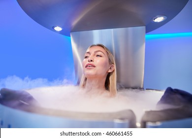 Portrait of young woman in a whole body cryotherapy chamber. Female getting cryo therapy at the cosmetology clinic.
