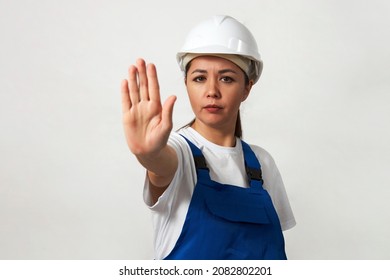 Portrait of young woman worker standing on white background with copy space. Female worker wearing workwear uniform and protective hard hat - Shutterstock ID 2082802201