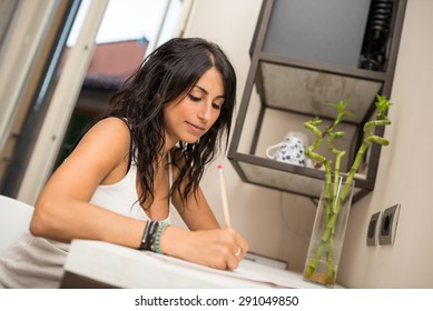 Portrait Of Young Woman Writing A Letter In Hotel Room.