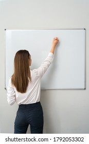 Portrait of young woman writing on white board during a presentation in conference room