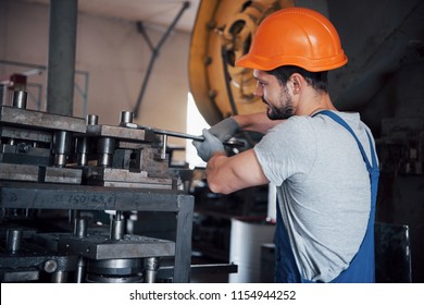 Portrait of a young worker in a hard hat at a large metalworking plant. The engineer serves the machines and manufactures parts for gas equipment. - Shutterstock ID 1154944252