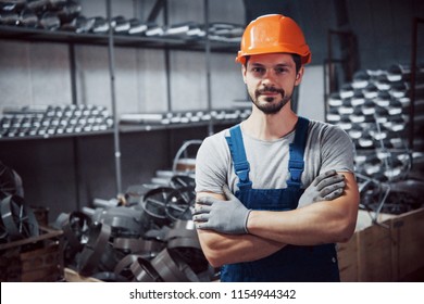Portrait Of A Young Worker In A Hard Hat At A Large Metalworking Plant. Shiftman On The Warehouse Of Finished Products.
