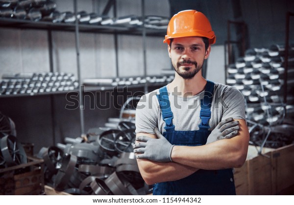 Portrait\
of a young worker in a hard hat at a large metalworking plant.\
Shiftman on the warehouse of finished\
products.