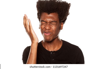 Portrait of young worried african american modern man slapped himself in the face on white background
