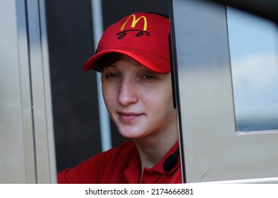 Portraitb Of Young Girl Looking Out Pick Up Window Of The Restaurant, Logo MCdonald's On A Cap. May 25, 2012. Chernigiv, Ukraine