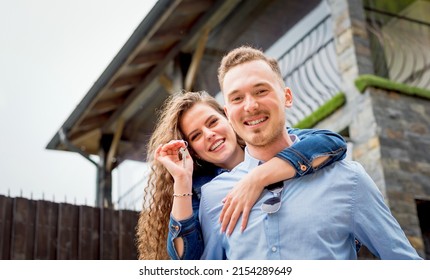 Portraitof Smiling Couple Standing Outside Near Their New House Recently Bought