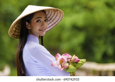 Portraits of cute lady with Vietnam culture traditional dress, Ao dai is famous and holding lotus flowers.