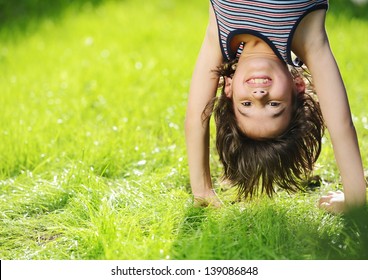 Portraits of happy kids playing upside down outdoors in summer park