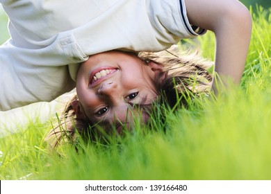 Portraits Of Happy Kids Playing Upside Down Outdoors In Summer Park Walking On Hands